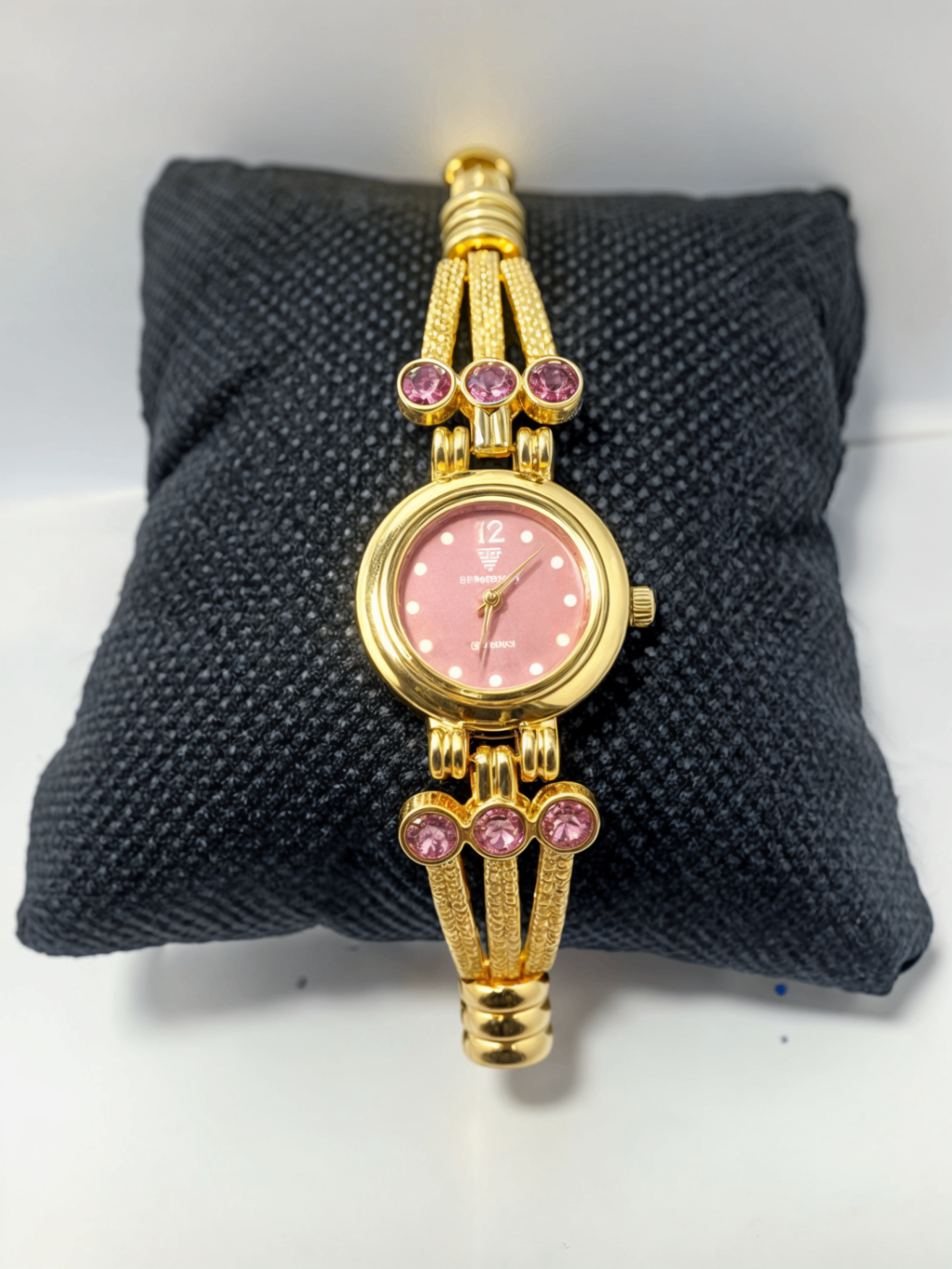 pink stones gold color watch on black pillow